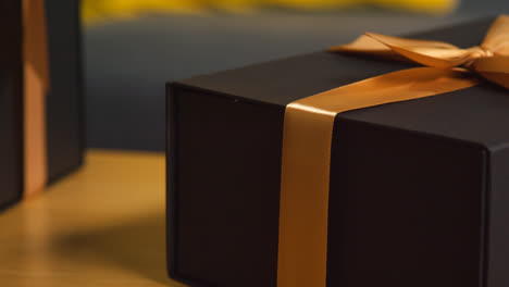 Close-Up-Of-Man-Picking-Up-Gift-Wrapped-Present-From-Table-In-Lounge-At-Home